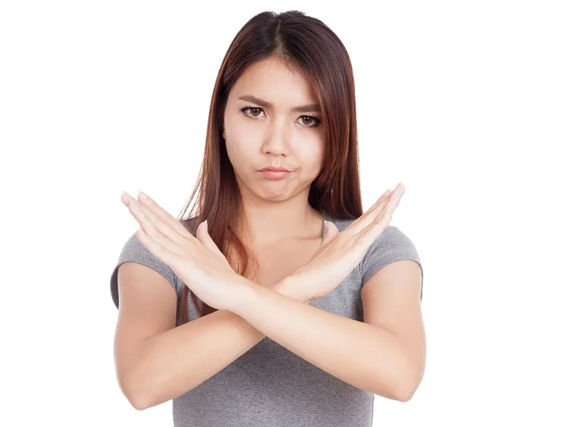No Means No Young woman with long brown hair stands with her arms crossed and hands open across her chest; she is clearly saying 'NO' with her body.